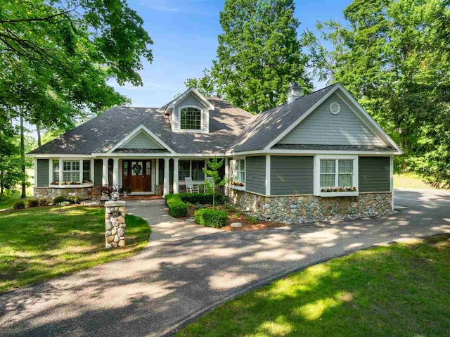 690 Woodhill Unit 6, Harbor Springs, MI 49740 - view of front facade featuring stone siding, a front lawn, a porch, and roof with shingles
