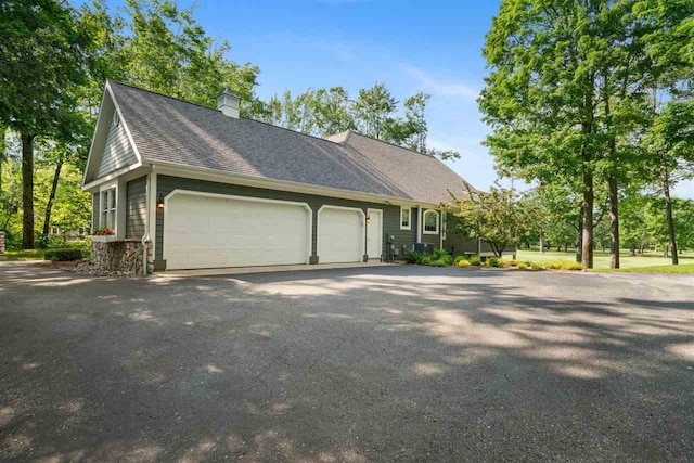 690 Woodhill Unit 6, Harbor Springs, MI 49740 - view of front of property featuring an attached garage, driveway, a chimney, and a shingled roof