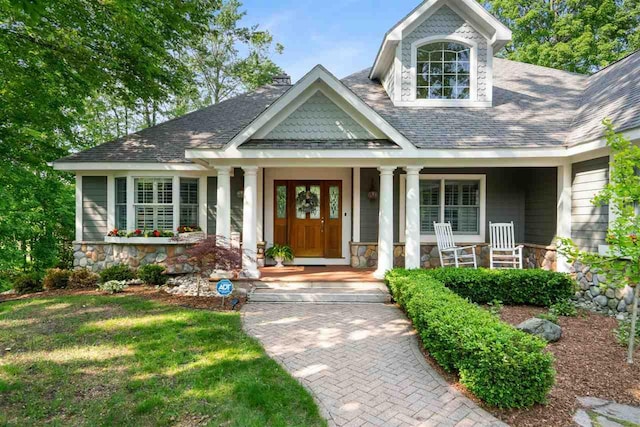 690 Woodhill Unit 6, Harbor Springs, MI 49740 - view of front of property with stone siding, covered porch, and roof with shingles