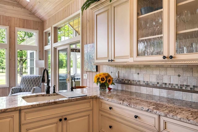 690 Woodhill Unit 6, Harbor Springs, MI 49740 - kitchen with cream cabinets, backsplash, light stone countertops, and vaulted ceiling