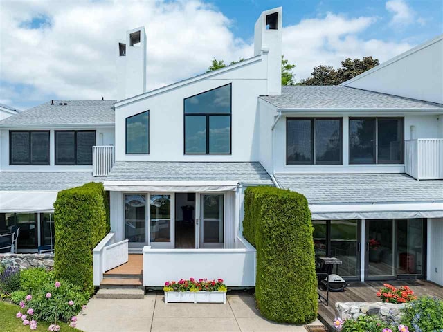 528 E Bay St Unit 30, Harbor Springs, MI 49740 - view of front facade featuring a wooden deck, a shingled roof, stucco siding, and a chimney