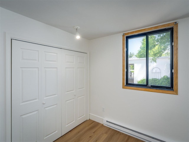 528 E Bay St Unit 30, Harbor Springs, MI 49740 - unfurnished bedroom featuring a baseboard radiator, light wood finished floors, and a closet