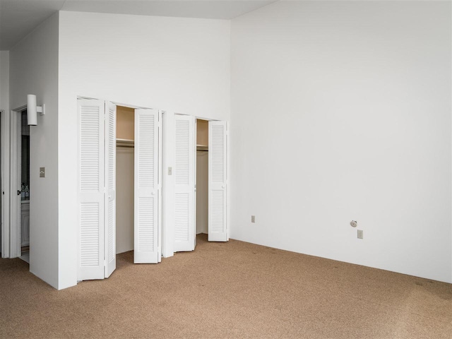 528 E Bay St Unit 30, Harbor Springs, MI 49740 - unfurnished bedroom with light carpet, two closets, and a towering ceiling