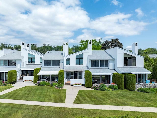 528 E Bay St Unit 30, Harbor Springs, MI 49740 - view of front of house with a front lawn, a chimney, and stucco siding