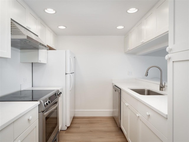 528 E Bay St Unit 30, Harbor Springs, MI 49740 - kitchen with appliances with stainless steel finishes, under cabinet range hood, white cabinetry, recessed lighting, and light countertops