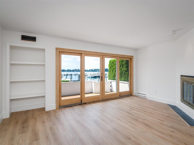 528 E Bay St Unit 30, Harbor Springs, MI 49740 - unfurnished living room with baseboard heating, french doors, wood finished floors, built in features, and a water view