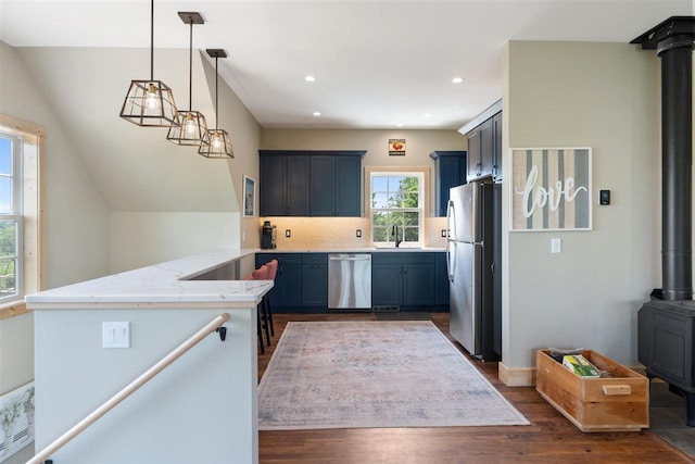 9235 Bailey Rd, East Jordan, MI 49727 - kitchen with appliances with stainless steel finishes, a wood stove, a peninsula, dark wood finished floors, and tasteful backsplash