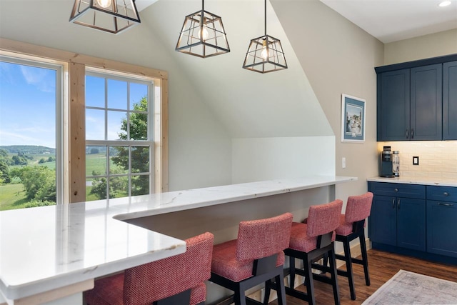 9235 Bailey Rd, East Jordan, MI 49727 - kitchen with blue cabinetry, dark wood-type flooring, tasteful backsplash, a kitchen breakfast bar, and vaulted ceiling