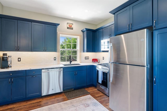 9235 Bailey Rd, East Jordan, MI 49727 - kitchen with appliances with stainless steel finishes, blue cabinetry, dark wood finished floors, recessed lighting, and decorative backsplash