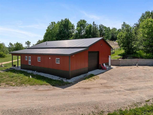 9235 Bailey Rd, East Jordan, MI 49727 - view of home's exterior with a detached garage, driveway, an outbuilding, and a metal roof