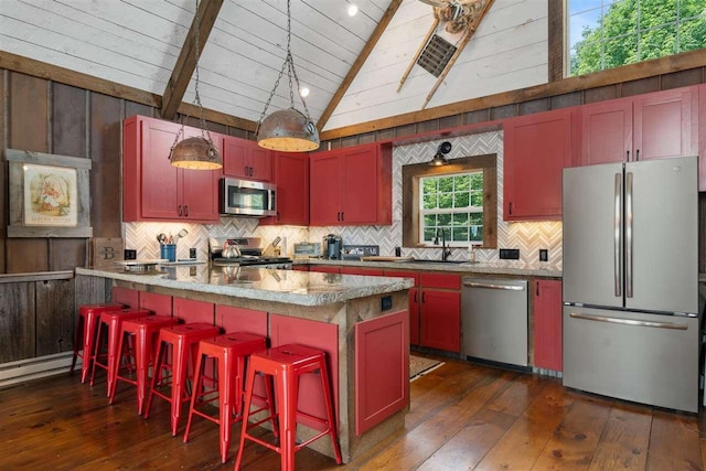 9235 Bailey Rd, East Jordan, MI 49727 - kitchen featuring appliances with stainless steel finishes, dark wood-type flooring, decorative backsplash, and a breakfast bar area