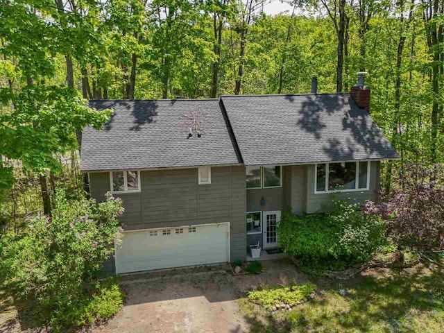 104 Meadow Wood Dr, Harbor Springs, MI 49740 - view of front of house featuring a chimney, a shingled roof, concrete driveway, and a garage
