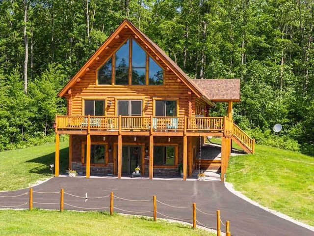 899 S State Rd, Harbor Springs, MI 49740 - view of front facade with log exterior, a wooden deck, and a front yard