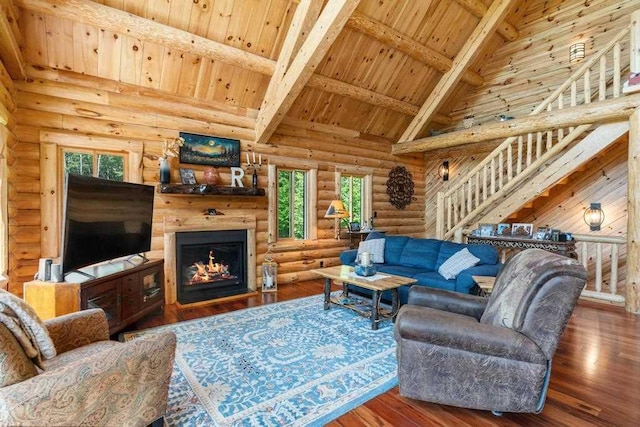899 S State Rd, Harbor Springs, MI 49740 - living room featuring log walls, a wood ceiling with exposed beams, wood-type flooring, stairs, and a lit fireplace