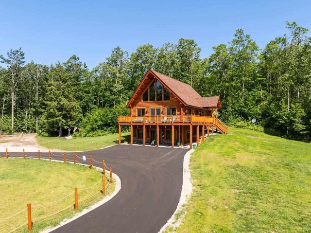 899 S State Rd, Harbor Springs, MI 49740 - log home with a front lawn, a wooden deck, asphalt driveway, and a view of trees