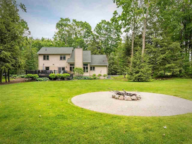 6598 Forest Way, Harbor Springs, MI 49740 - rear view of property with an outdoor fire pit, a wooden deck, a yard, and a chimney