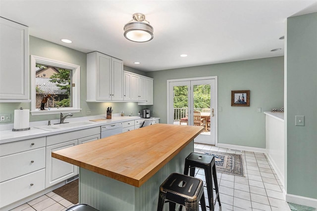 1835 Bluffs Edge, Harbor Springs, MI 49740 - kitchen with white dishwasher, white cabinets, butcher block countertops, a kitchen breakfast bar, and recessed lighting