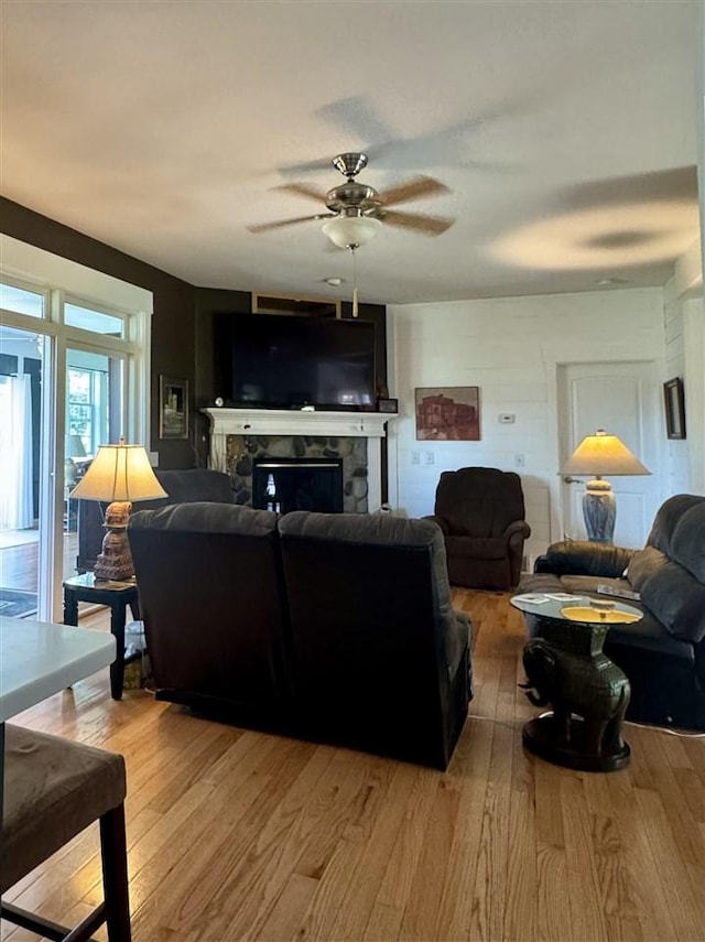 7570 Bay Meadow Dr, Harbor Springs, MI 49740 - living area featuring a stone fireplace, light wood-style floors, and ceiling fan