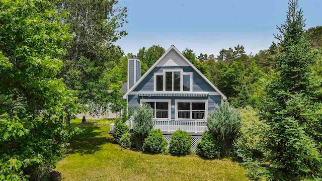 1885 Lalonde Rd, East Jordan, MI 49727 - back of property with a lawn, a chimney, and a deck