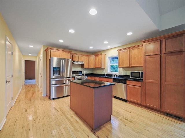 1885 Lalonde Rd, East Jordan, MI 49727 - kitchen featuring stainless steel appliances, light wood finished floors, a kitchen island, dark countertops, and under cabinet range hood
