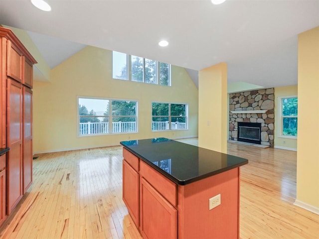 1885 Lalonde Rd, East Jordan, MI 49727 - kitchen featuring open floor plan, light wood-type flooring, vaulted ceiling, a kitchen island, and a stone fireplace