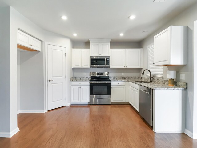510 Bucklebury Rd, Greer, SC 29651 - kitchen with appliances with stainless steel finishes, wood finished floors, white cabinetry, light stone countertops, and recessed lighting