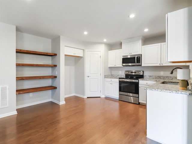510 Bucklebury Rd, Greer, SC 29651 - kitchen with appliances with stainless steel finishes, light stone counters, white cabinets, recessed lighting, and wood finished floors