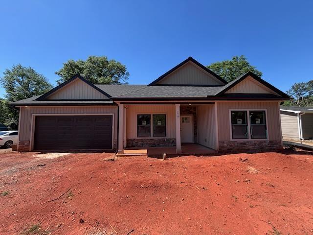 179 Cedar Ave, Wellford, SC 29385 - view of front of property featuring an attached garage, driveway, a shingled roof, and stone siding