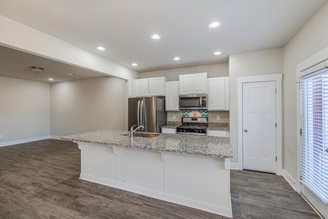 105 Lerner Ct, Spartanburg, SC 29301 - kitchen featuring appliances with stainless steel finishes, dark wood-style flooring, white cabinets, an island with sink, and a kitchen breakfast bar