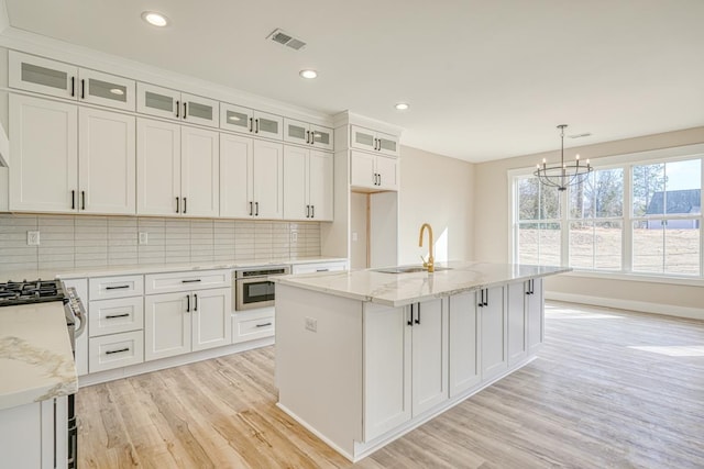 155 Chestnut Dr, Woodruff, SC 29388 - kitchen featuring appliances with stainless steel finishes, light wood-type flooring, a chandelier, light stone counters, and backsplash