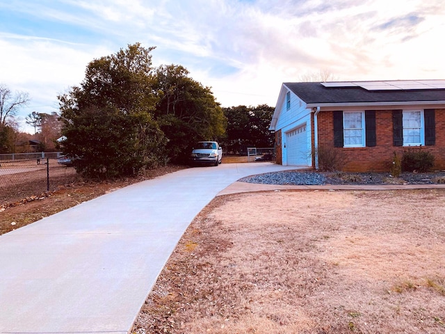 107 Mulberry St, Inman, SC 29349 - view of home's exterior with concrete driveway, brick siding, solar panels, a garage, and a shingled roof