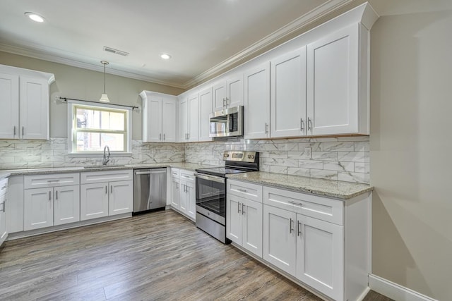 139 Floyd Meadow Dr, Inman, SC 29349 - kitchen featuring stainless steel appliances, white cabinets, light wood finished floors, crown molding, and decorative backsplash