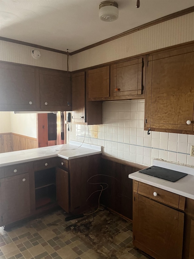 513 Peach Orchard Rd, Union, SC 29379 - kitchen featuring crown molding, backsplash, light countertops, wallpapered walls, and a wainscoted wall