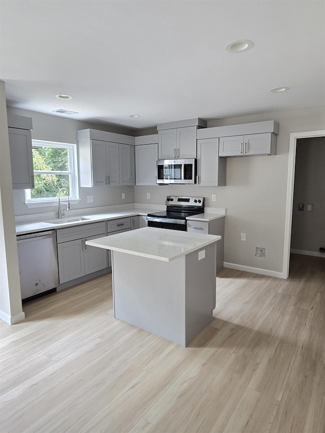 218 Caulder Cir, Spartanburg, SC 29306 - kitchen featuring appliances with stainless steel finishes, gray cabinetry, light countertops, light wood-type flooring, and a kitchen island