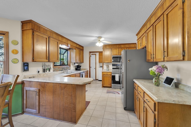 1114 Edisto Dr, Spartanburg, SC 29302 - kitchen featuring appliances with stainless steel finishes, light countertops, a peninsula, brown cabinets, and washing machine and clothes dryer