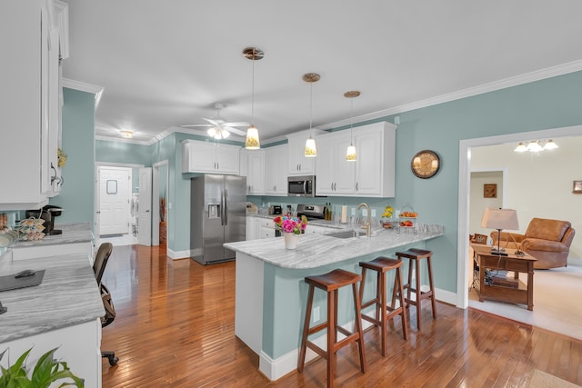 626 S Sweetwater Hills Dr, Moore, SC 29369 - kitchen featuring appliances with stainless steel finishes, a peninsula, white cabinets, a breakfast bar, and hardwood / wood-style flooring