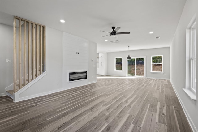 101 Daisy Ln, Easley, SC 29640 - unfurnished living room featuring wood finished floors, a ceiling fan, a glass covered fireplace, recessed lighting, and stairs