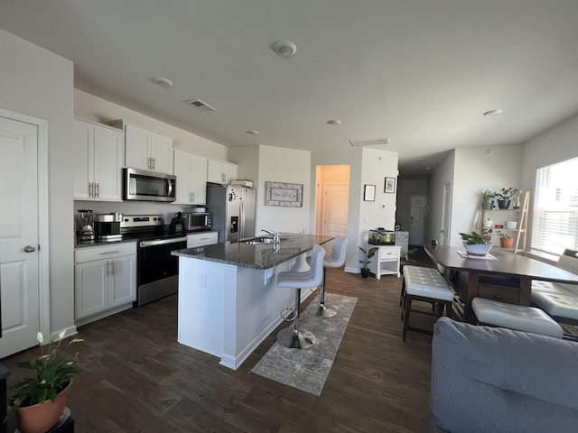 1341 Wunder Way, Boiling Springs, SC 29316 - kitchen with stainless steel appliances, a kitchen island with sink, dark wood-style flooring, a breakfast bar area, and white cabinets