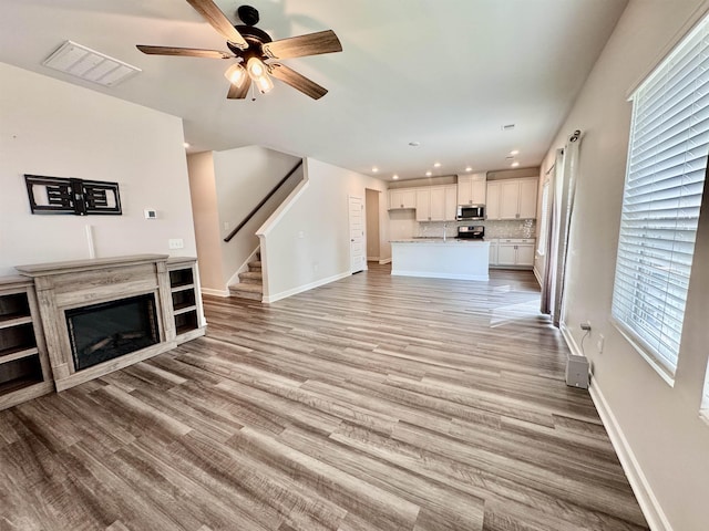 637 Grays Creek Rd, Spartanburg, SC 29303 - unfurnished living room featuring stairway, ceiling fan, a glass covered fireplace, recessed lighting, and light wood finished floors