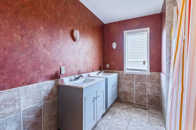 1109 Hemlock Dr, Shelby, NC 28150 - bathroom with double vanity, tile walls, a textured ceiling, and wainscoting