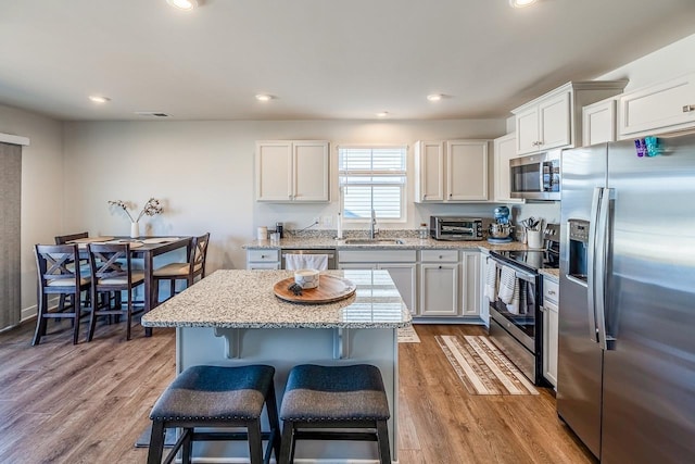 2086 Wexley Dr, Boiling Springs, SC 29316 - kitchen featuring appliances with stainless steel finishes, a kitchen breakfast bar, light stone counters, white cabinets, and a center island