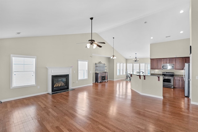 237 Medoc Ln, Moore, SC 29369 - unfurnished living room with high vaulted ceiling, a glass covered fireplace, a ceiling fan, wood finished floors, and a chandelier