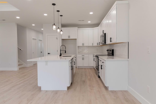 114 Robin Hill Dr, Inman, SC 29349 - kitchen featuring stainless steel appliances, decorative backsplash, light wood-type flooring, white cabinetry, and decorative light fixtures