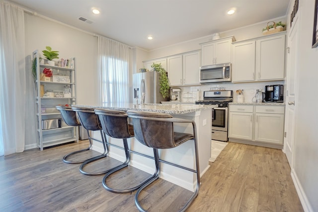1470 Talley Ridge Dr, Woodruff, SC 29388 - kitchen featuring appliances with stainless steel finishes, ornamental molding, backsplash, light wood-style flooring, and an island with sink