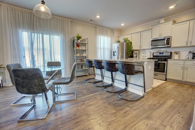 1470 Talley Ridge Dr, Woodruff, SC 29388 - kitchen with appliances with stainless steel finishes, a center island, ornamental molding, tasteful backsplash, and light wood finished floors