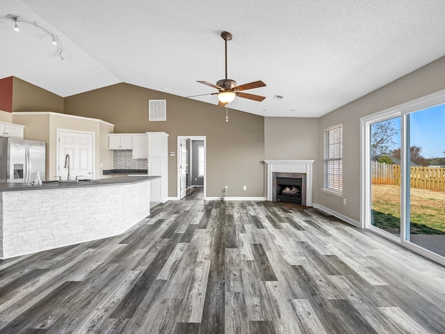 461 Candleglow Dr, Boiling Springs, SC 29316 - unfurnished living room featuring a fireplace with flush hearth, dark wood-style floors, ceiling fan, track lighting, and a textured ceiling