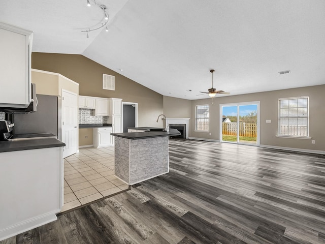 461 Candleglow Dr, Boiling Springs, SC 29316 - kitchen with dark countertops, a ceiling fan, a fireplace, backsplash, and light wood-type flooring