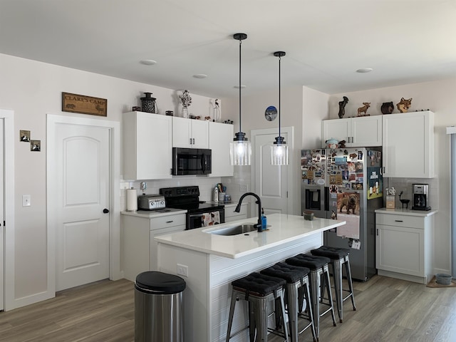 138 Lowe Rd, Chesnee, SC 29323 - kitchen featuring black appliances, tasteful backsplash, light wood-style floors, and a kitchen breakfast bar