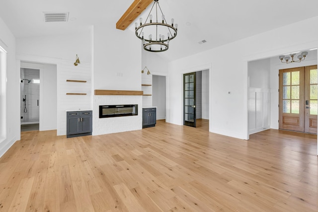 164 Triangle Pine Rd, Fountain Inn, SC 29644 - unfurnished living room with a chandelier, light wood-style flooring, a glass covered fireplace, beam ceiling, and high vaulted ceiling