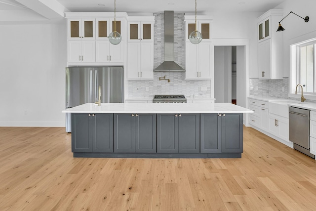 164 Triangle Pine Rd, Fountain Inn, SC 29644 - kitchen with wall chimney range hood, a spacious island, appliances with stainless steel finishes, light countertops, and light wood-type flooring